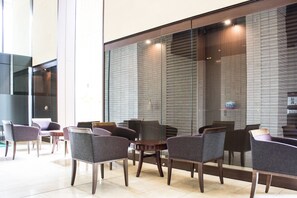 A modern interior with seating arrangements and a large glass wall. - Hotel Bestland (Tsukuba)