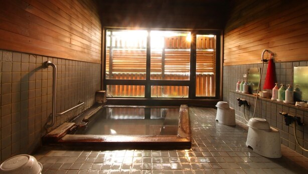 A traditional Japanese onsen with wooden walls, a wooden bathtub, and a tiled floor. - Le Vert Zao (Yamagata)