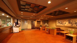 A hotel lobby with a reception desk, seating area, and artwork on the walls. - Le Vert Zao (Yamagata)