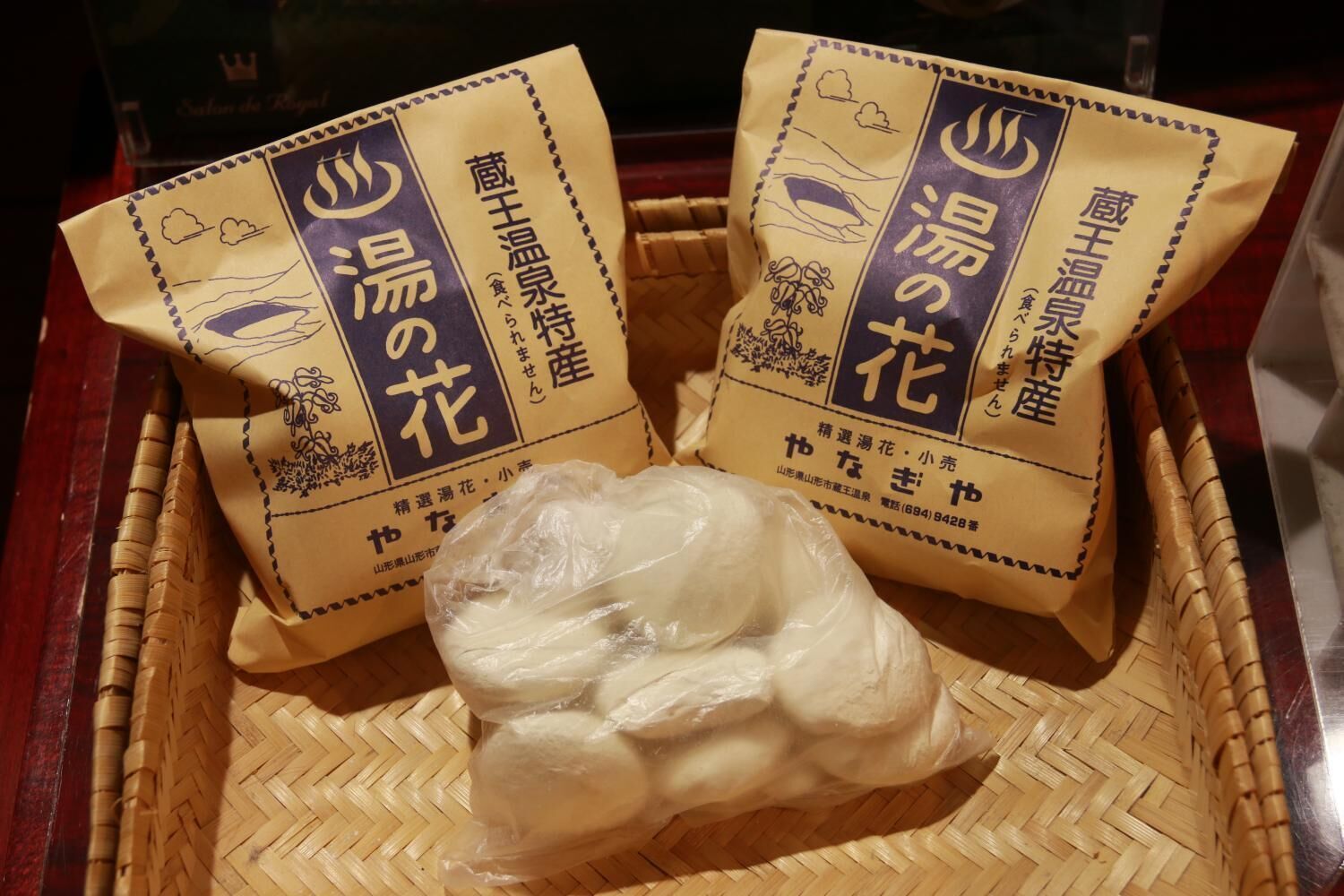 Two bags of Japanese rice with a plastic bag of rice in a woven basket.