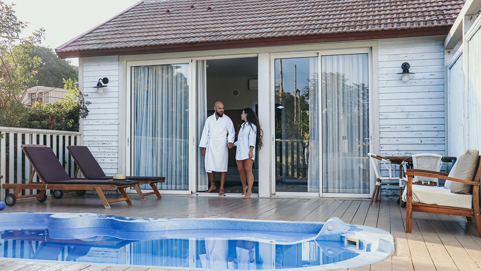 Zona junto a la piscina con piscina, sillas de descanso y una terraza cubierta.