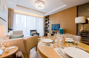 Een hotelkamer met een zithoek, een televisie, een boekenkast en een kroonluchter.