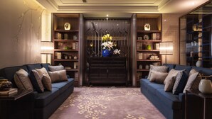 Una sala de estar moderna con un sofá azul, un tapete estampado y un jarrón decorativo con flores.
