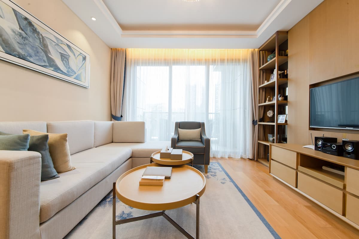 Un salon moderne comprenant un canapé, un fauteuil, une table basse, un téléviseur et une bibliothèque.