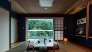 Une pièce de style japonais traditionnel, avec un sol recouvert de tatamis, un paravent shoji, une table en tatami et une vue sur une forêt, visible à travers une grande fenêtre.
