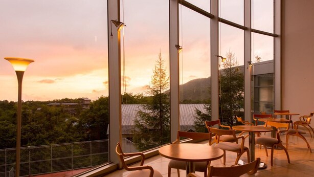 Un restaurant doté de grandes fenêtres offrant une vue sur un paysage montagneux au coucher du soleil.