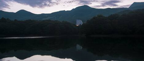 A lake reflecting mountains and a building with a distinctive roof.