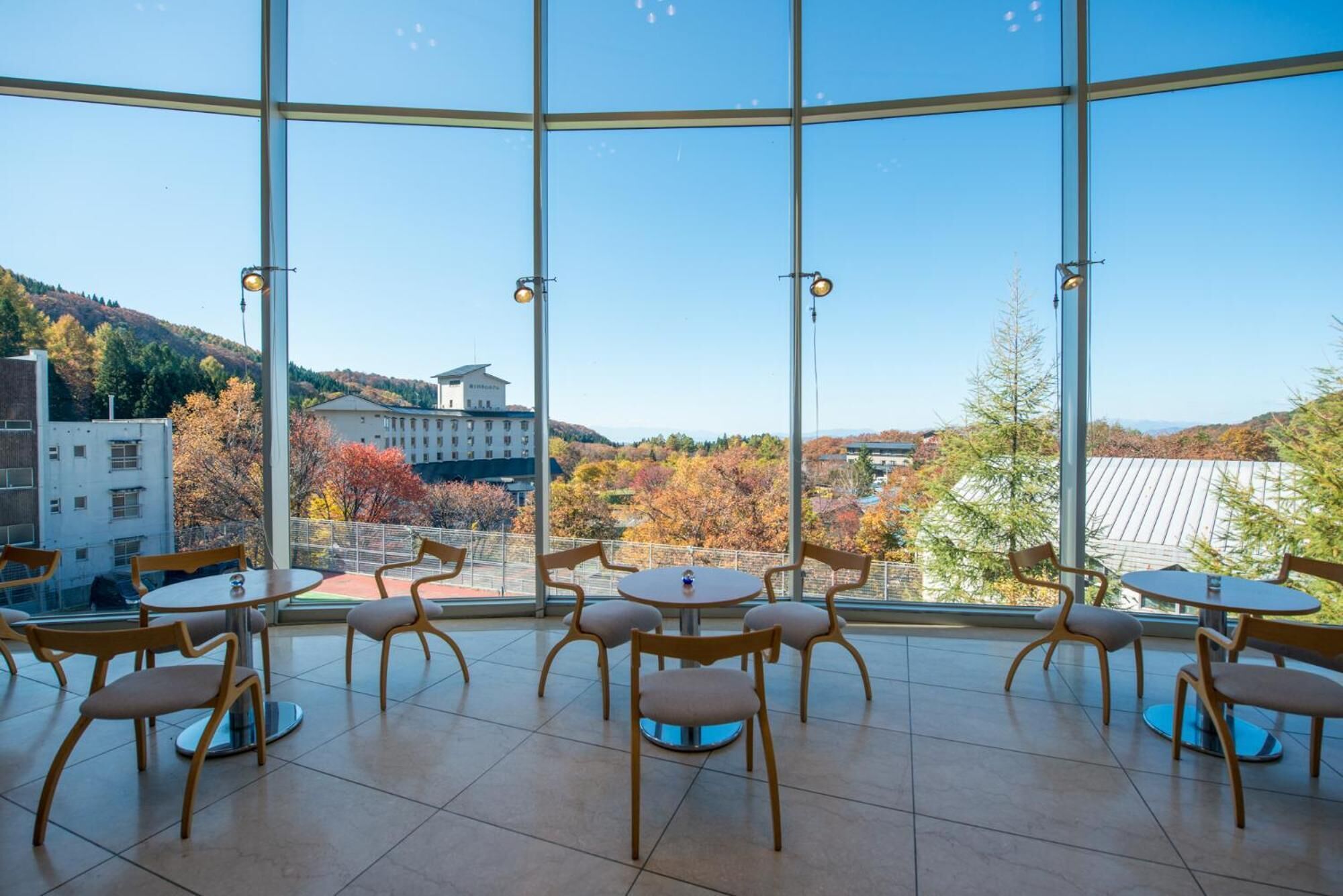 A modern interior with large windows offering a scenic view of autumn foliage and a distant building.