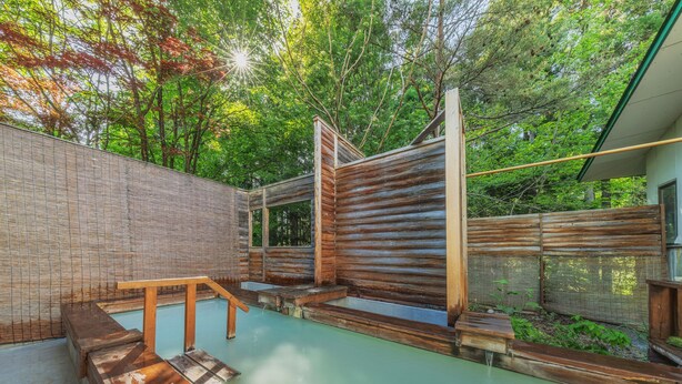 Un área de spa de madera con piscina, bancos y una valla de madera.
