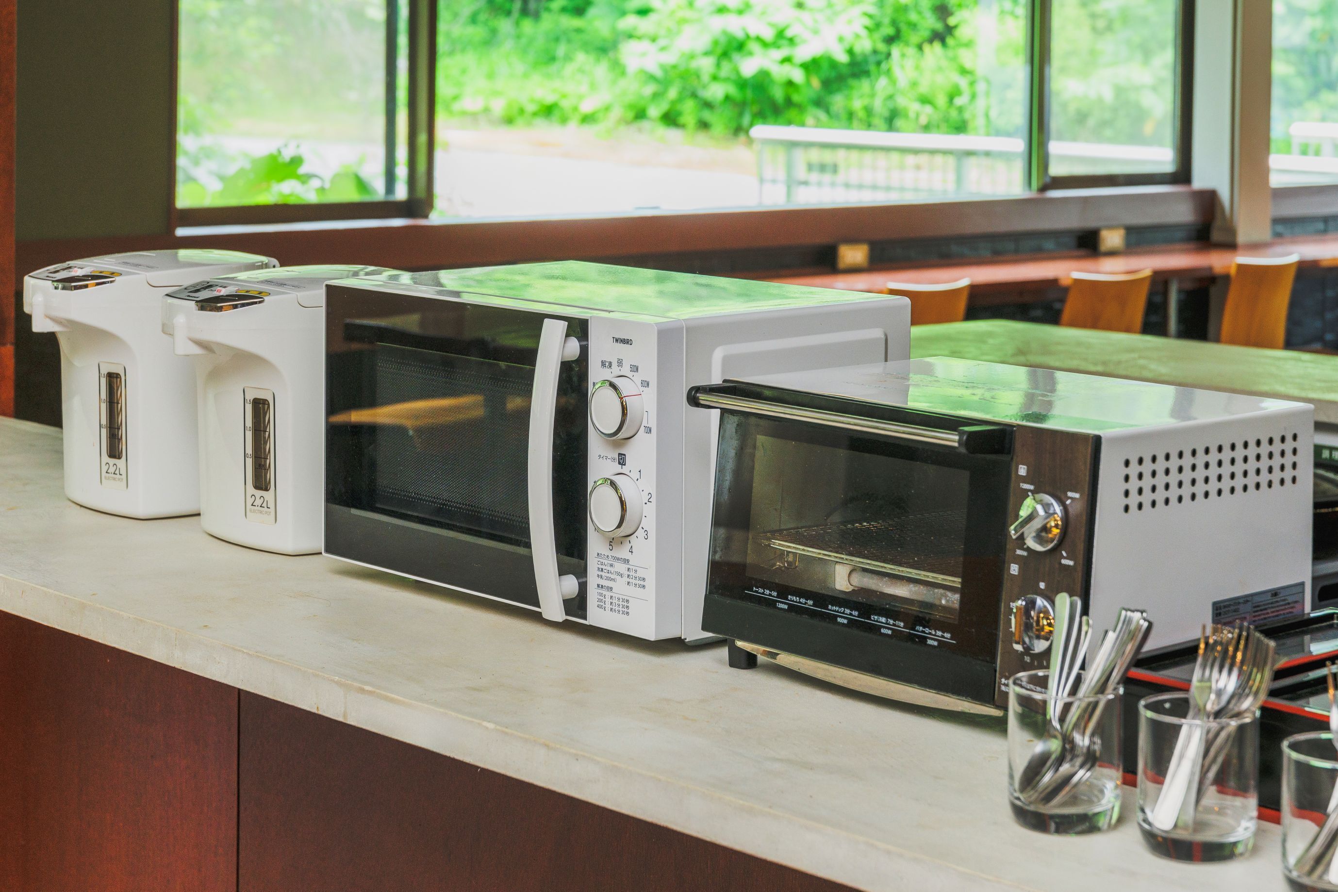 A kitchen with three different types of toasters and a microwave on the counter.