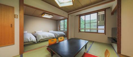 Ein traditioneller japanischer Raum mit Tatami-Boden, einem niedrigen Tisch und einer Futon-Liege.