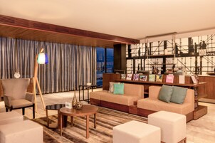 Una sala de estar moderna con un sofá, sillones, una mesa de centro y una lámpara.
