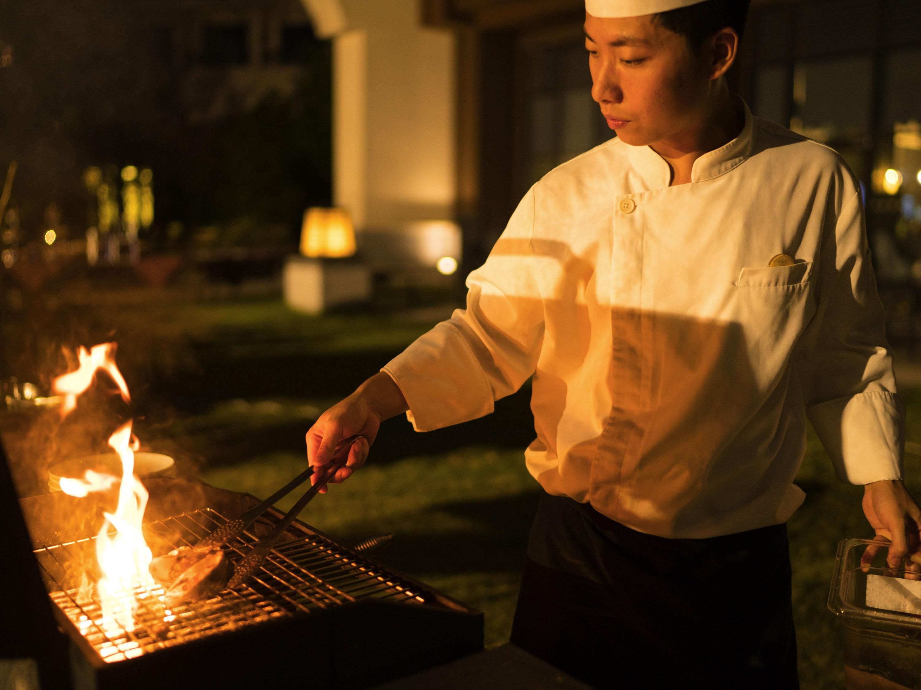 A chef grilling outdoors at night.