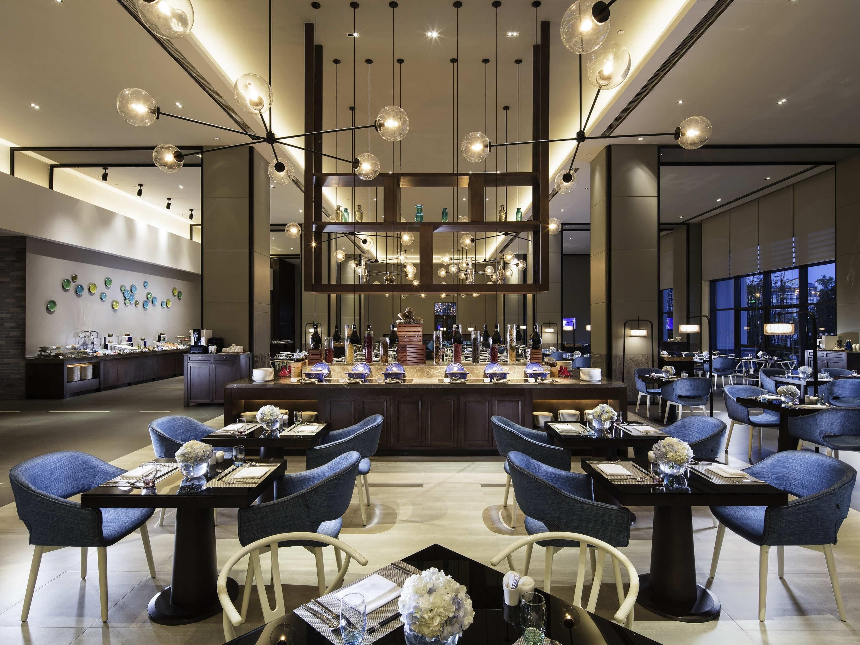 A modern hotel lobby with a central bar area, seating arrangements, and a decorative wall with plates.