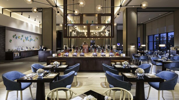 A modern hotel lobby with a central bar area, seating arrangements, and a decorative wall with plates. - Novotel Hefei Sunac (Hefei)