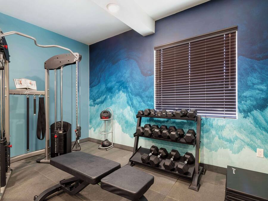 A gym with exercise equipment, a bench, and a rack of dumbbells.