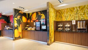 Un espace d’accueil moderne avec un comptoir en bois, un écran numérique et une fresque murale sur le thème des fruits.