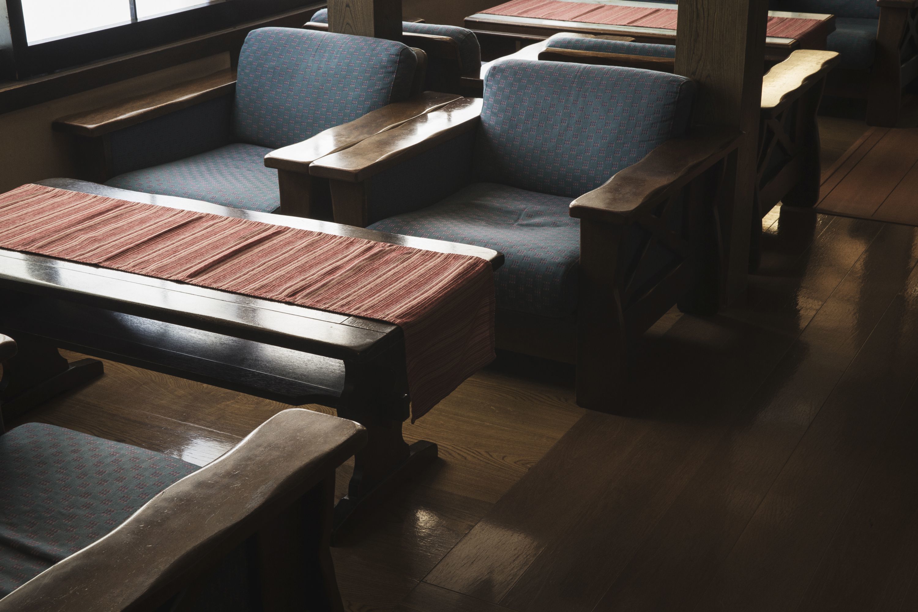 A restaurant interior with wooden tables and blue upholstered chairs.