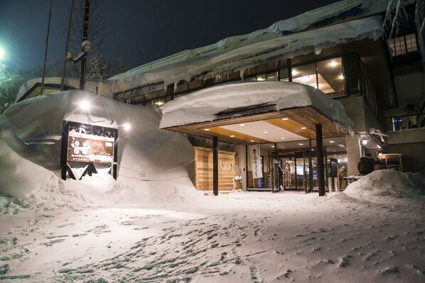 En hotellentrél med snötäckt omgivning och en väl synlig skylt.