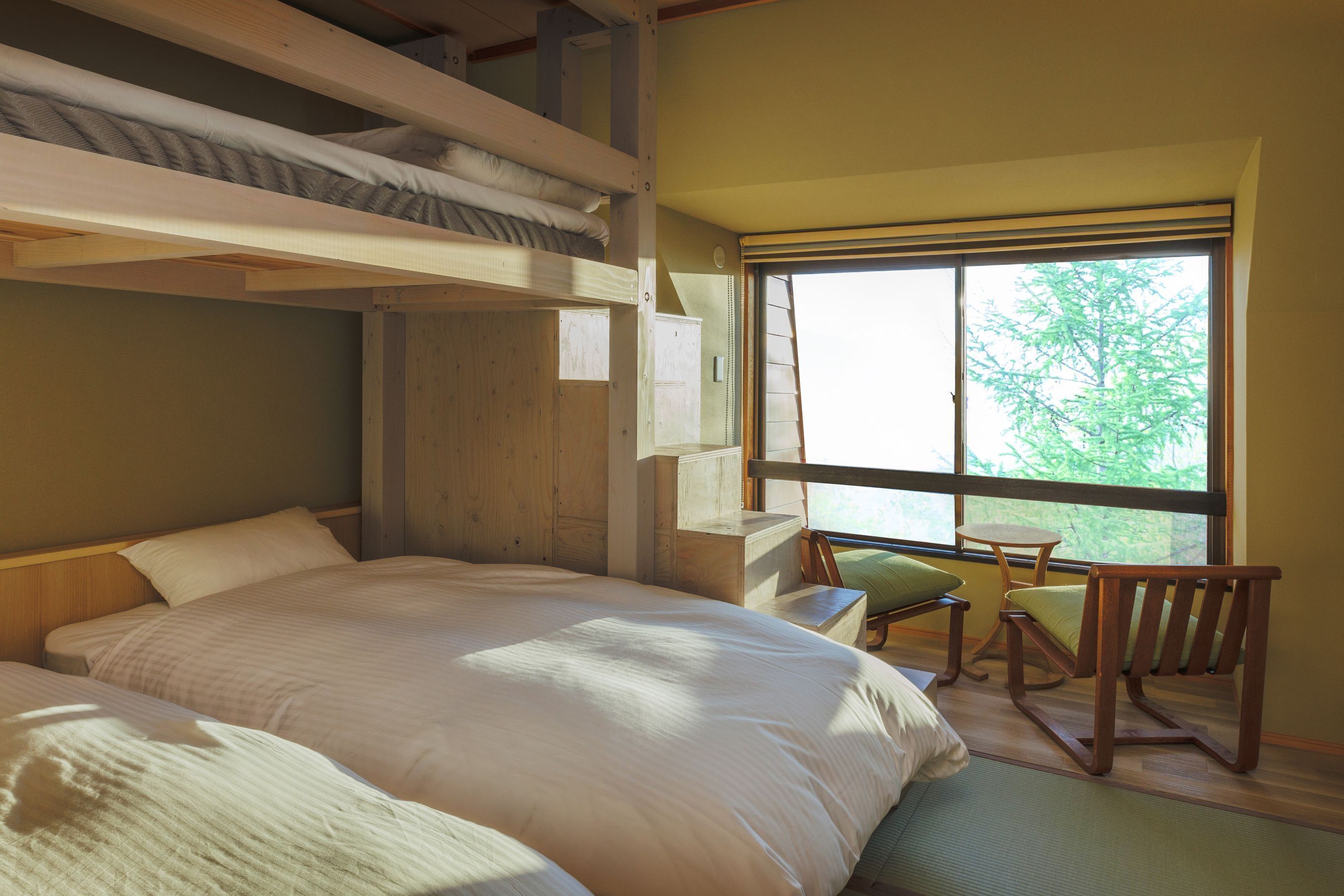 A room with a bunk bed, a desk, and a chair near a window.
