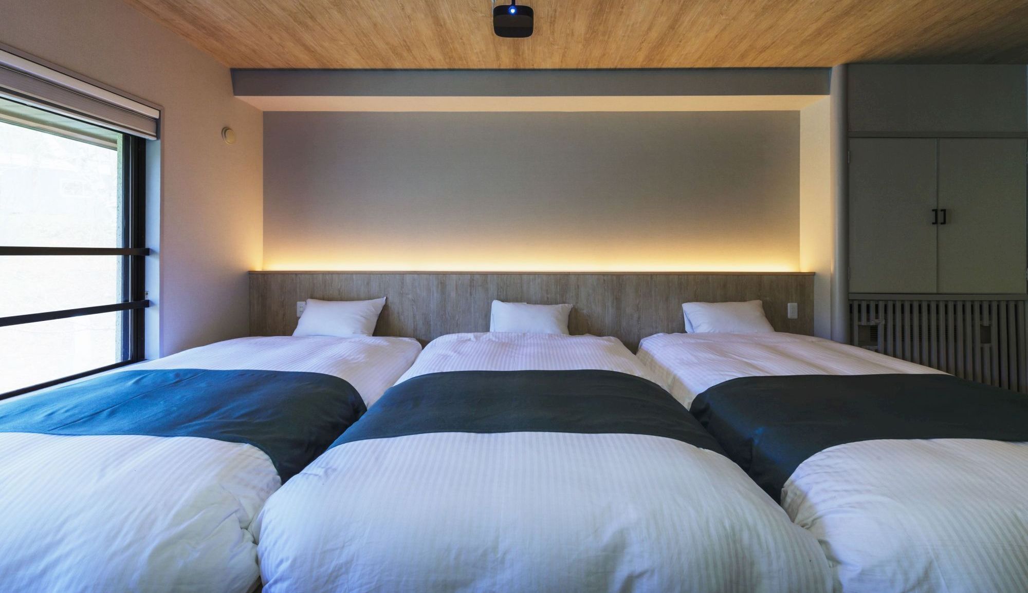 Une chambre d’hôtel avec trois lits, un plafond en bois et une vue sur l’extérieur.