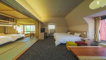 A hotel room with two beds, a wooden table, a small desk, and a window with curtains.