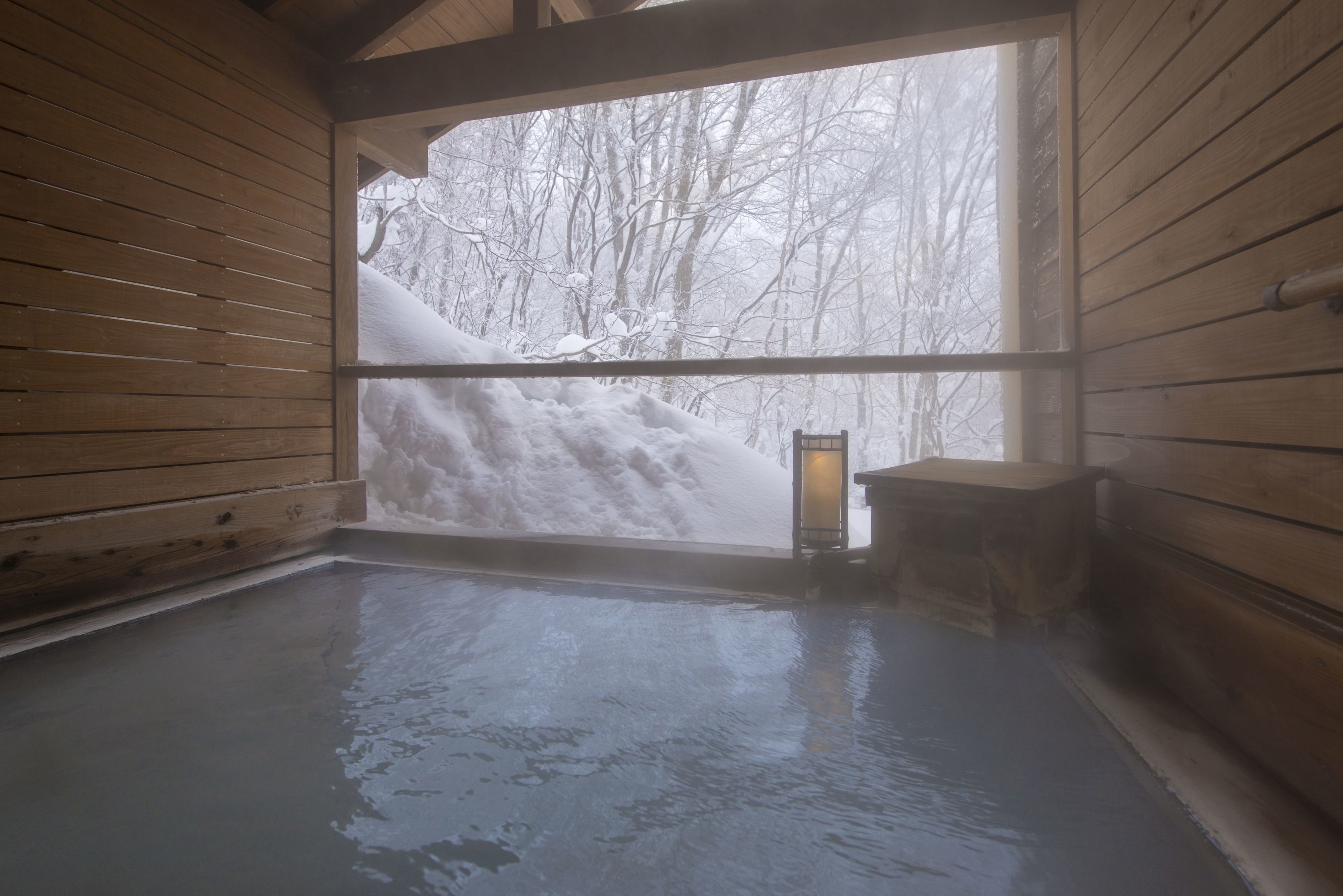 A wooden spa room with a large window overlooking a snowy landscape.