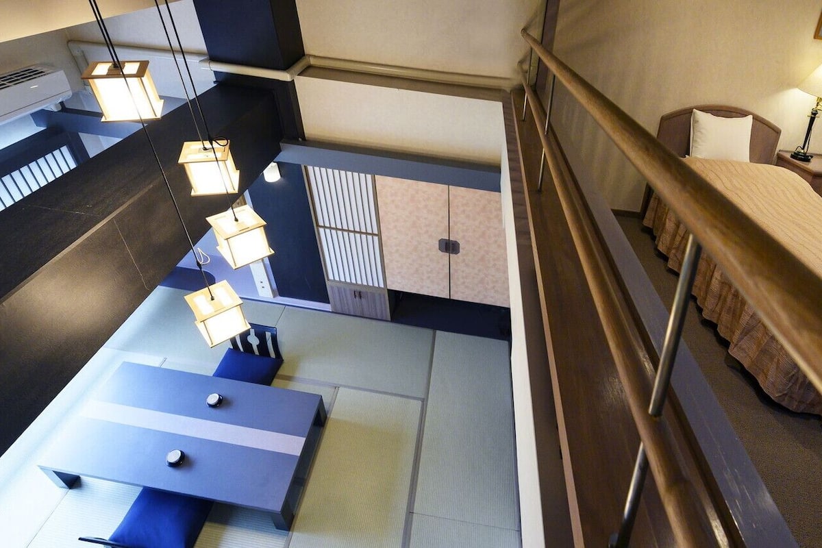 A hotel room with a bed, bedside tables, a desk, and a view of the outside.