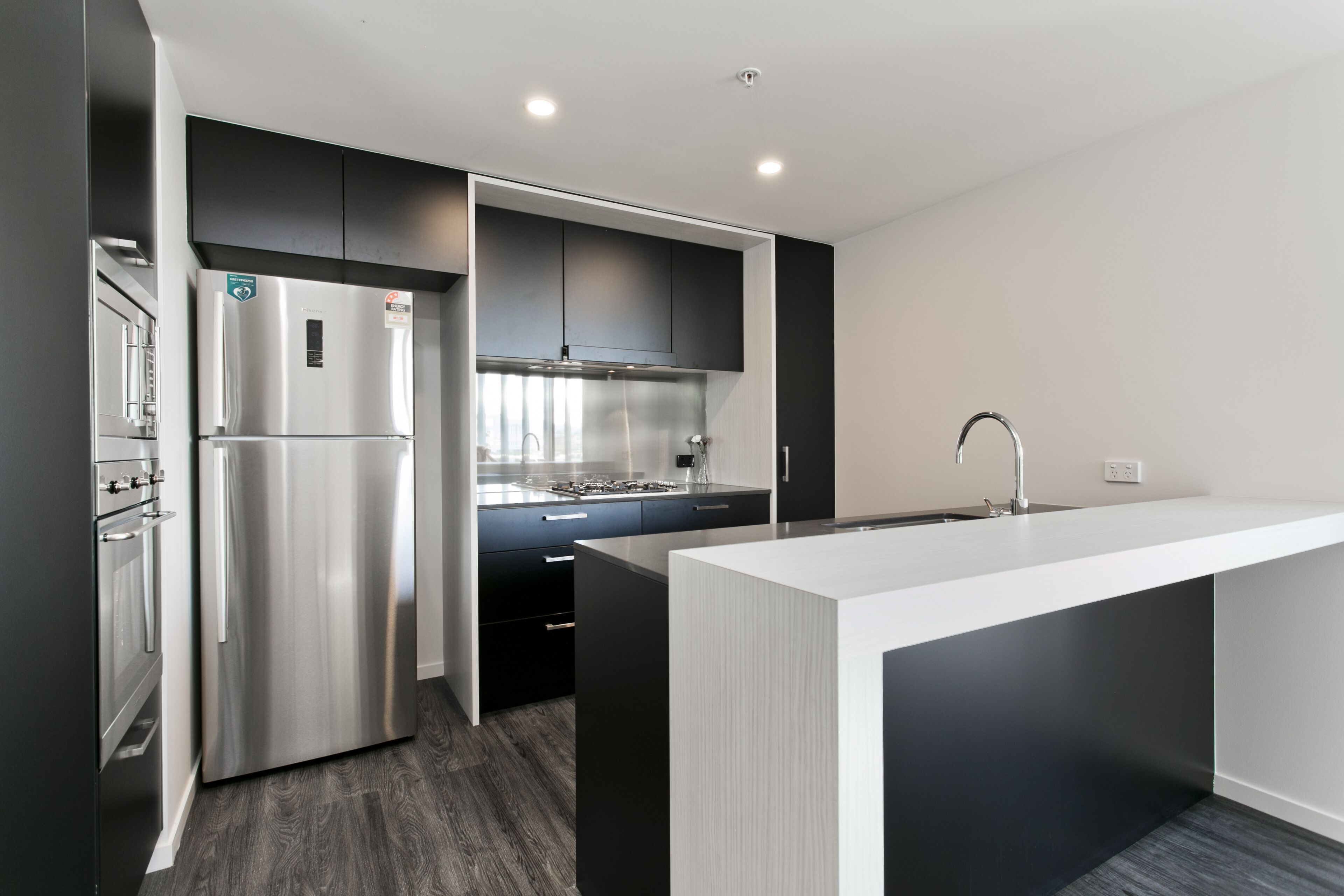 A modern kitchen with a stainless steel refrigerator, a built-in stove, and a white island with a sink.