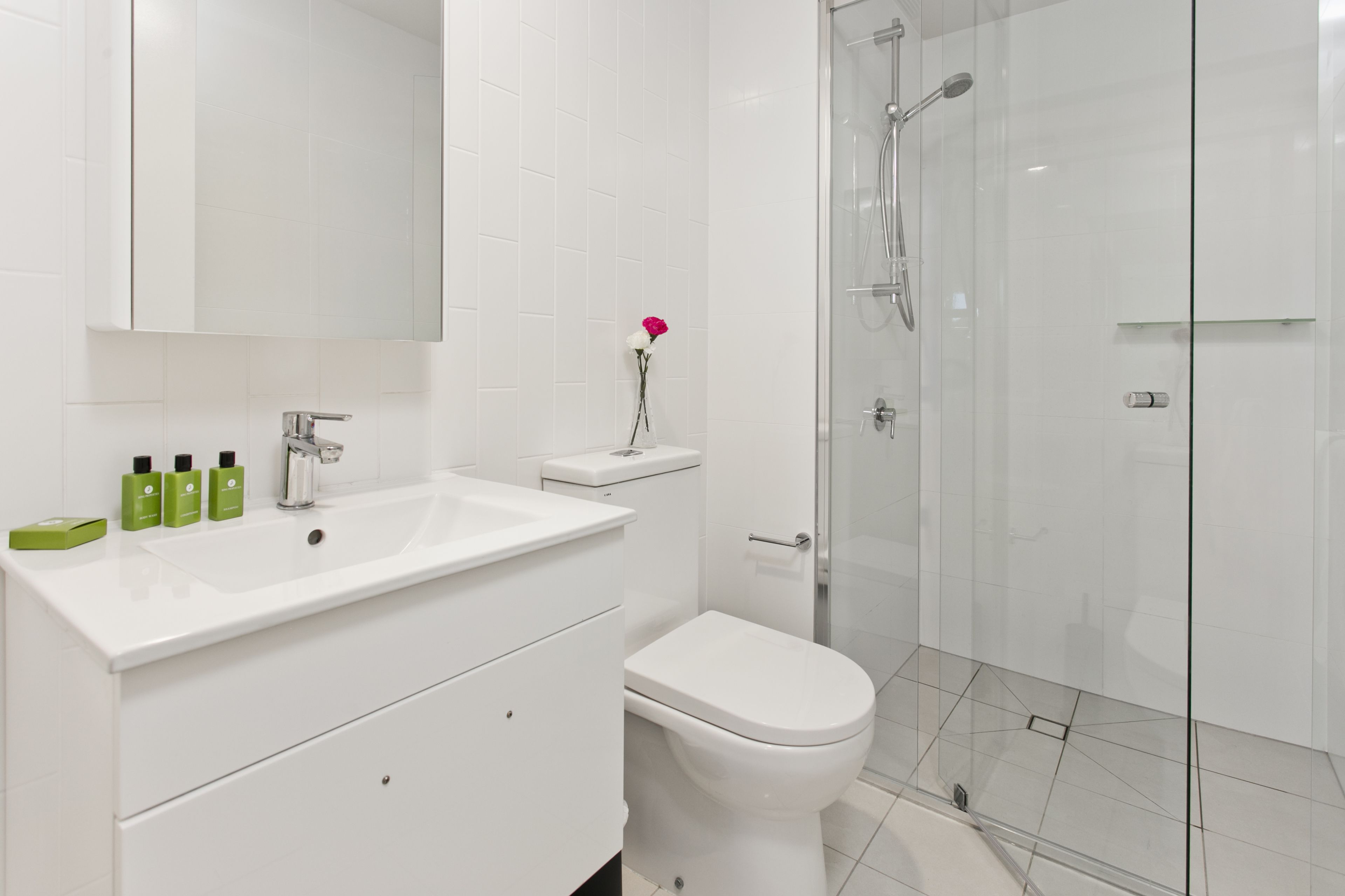 A modern bathroom with a white sink, toilet, and glass shower enclosure.