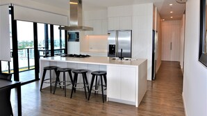 A modern kitchen with a central island, stainless steel appliances, and a view to the outside. - Soda Apartments by CLLIX (South Brisbane)