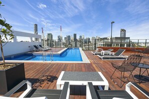 Una piscina al aire libre, sillones reclinables de piscina