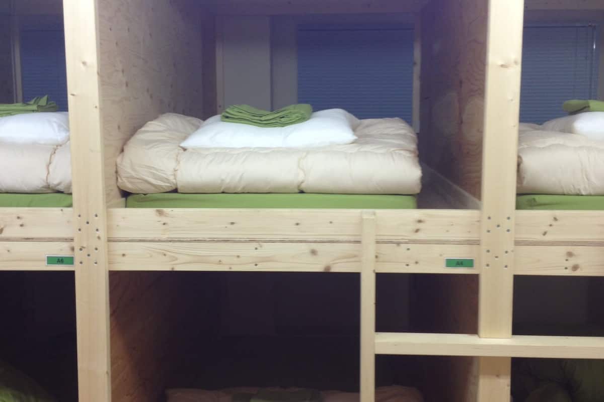 A bunk bed room with wooden frames and green bedding.