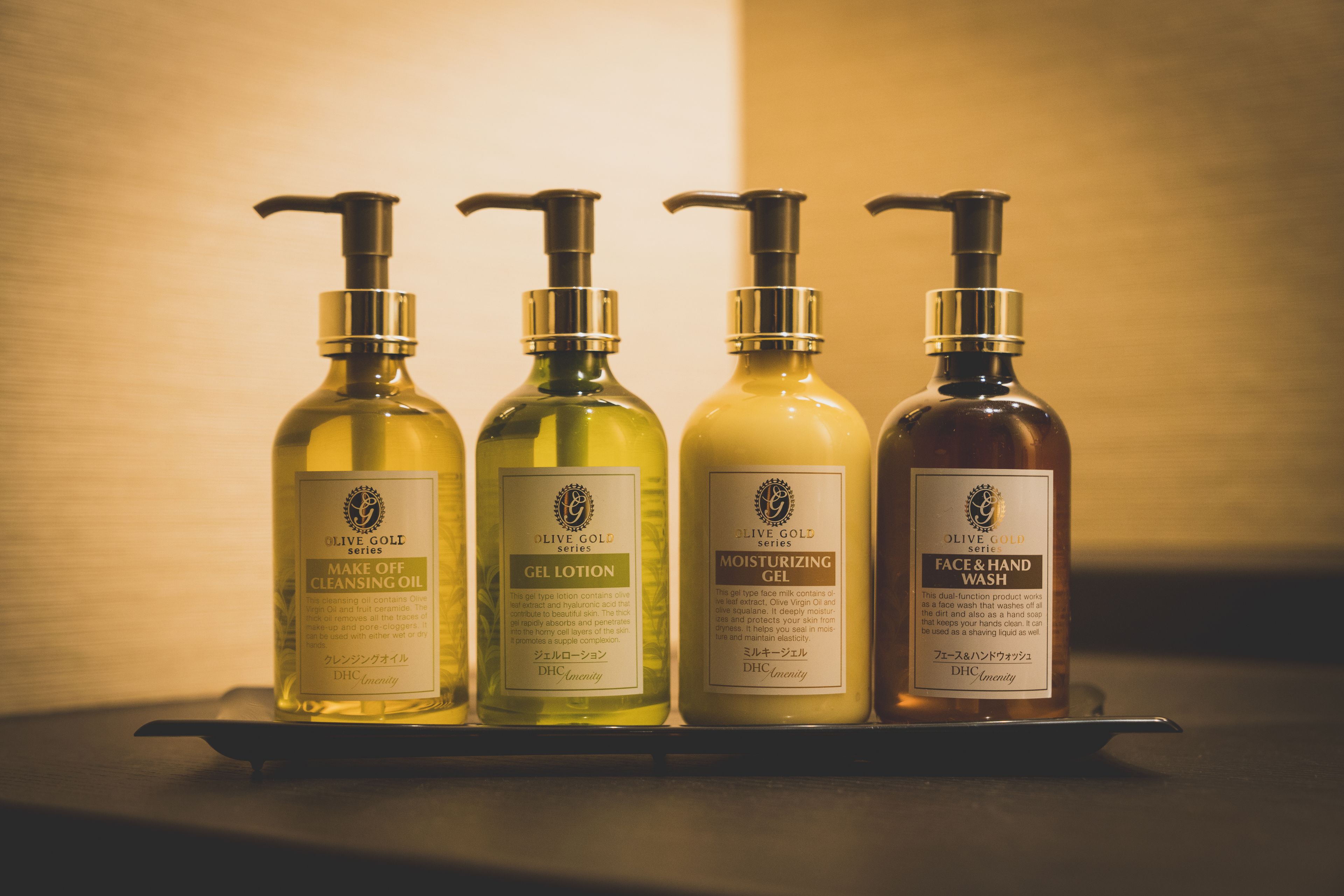 Four bottles of olive oil-based skincare products on a tray.