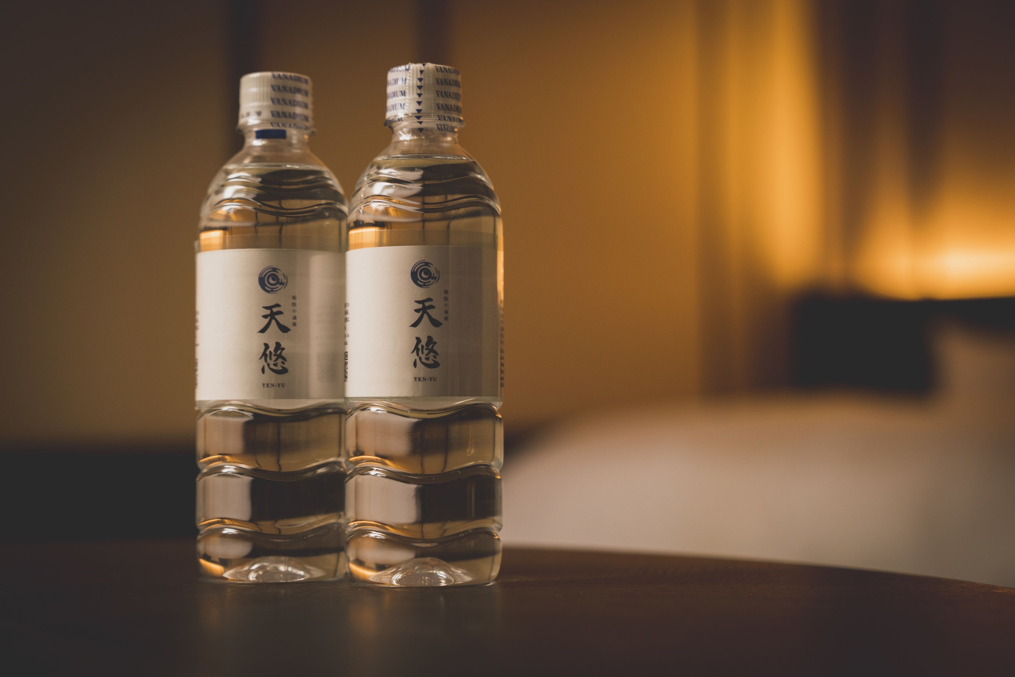Dos botellas de agua sobre una mesa con un fondo desenfocado.