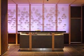 A reception desk with a modern design, featuring a geometric pattern on the wall behind it.