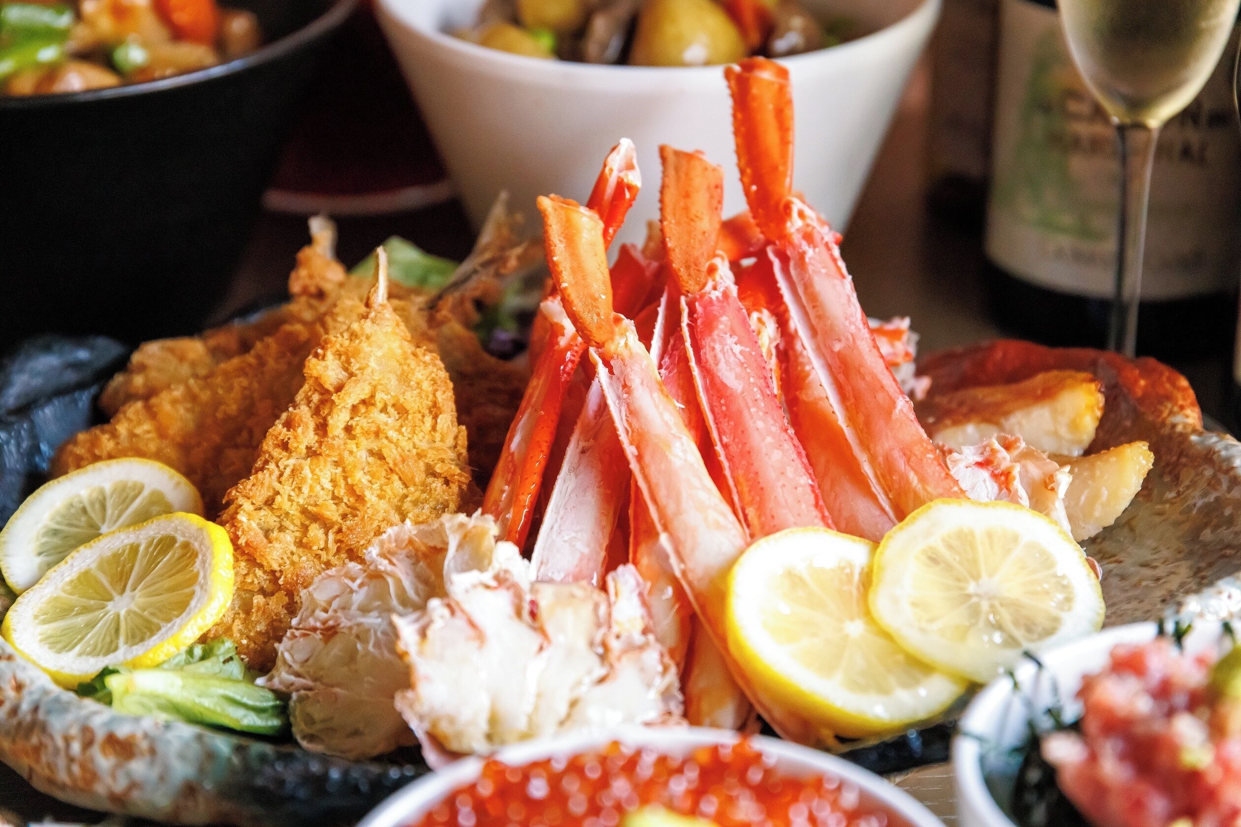 A seafood platter with various items including crab legs, a fried fish, and lemon slices.