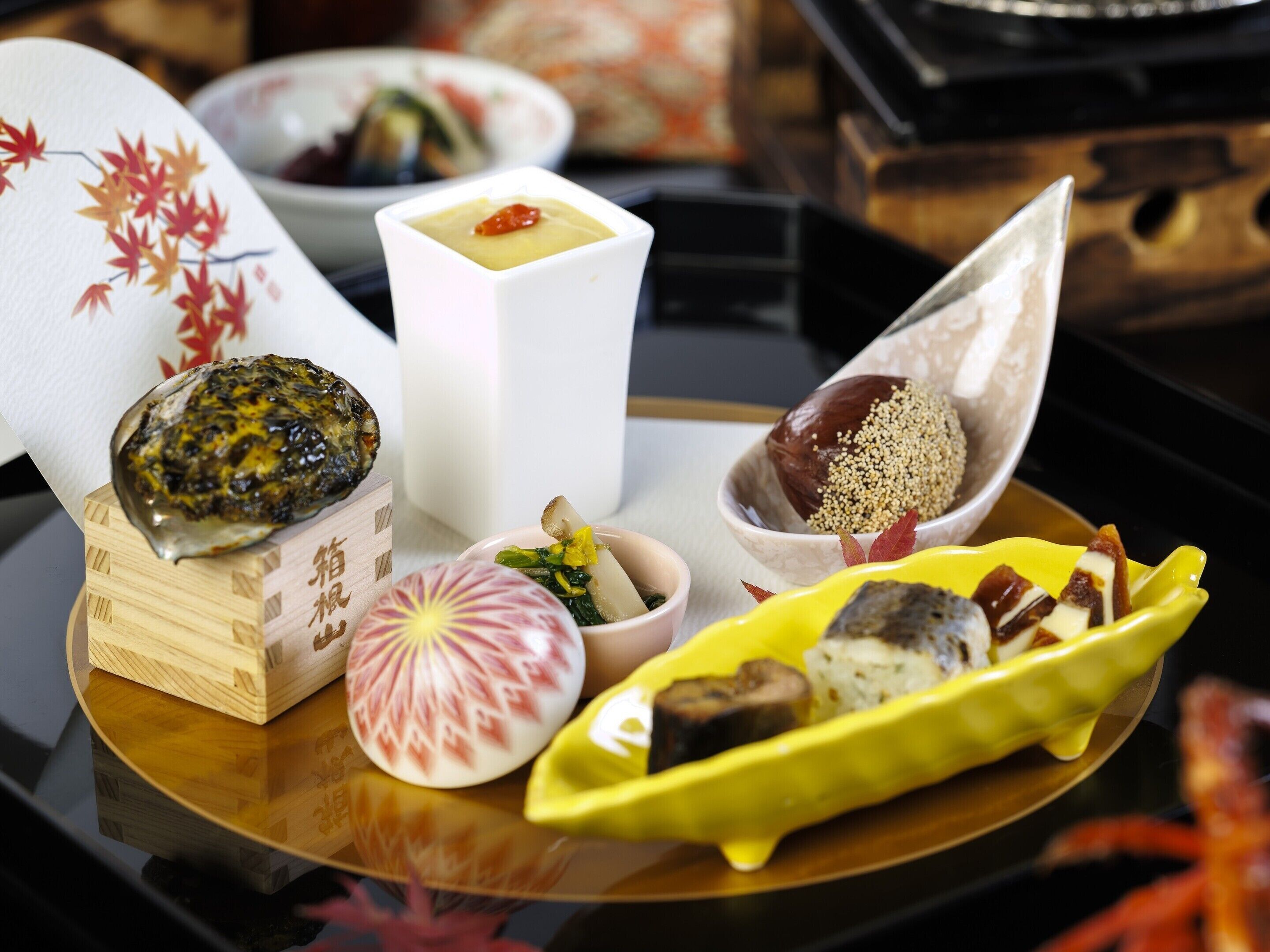 A variety of Japanese dishes on a table, including sushi, sashimi, and a bowl of rice with sesame seeds.