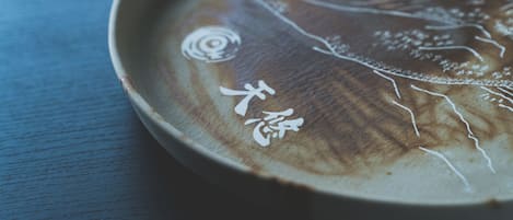 A close-up of a ceramic plate with intricate white designs and Japanese characters.