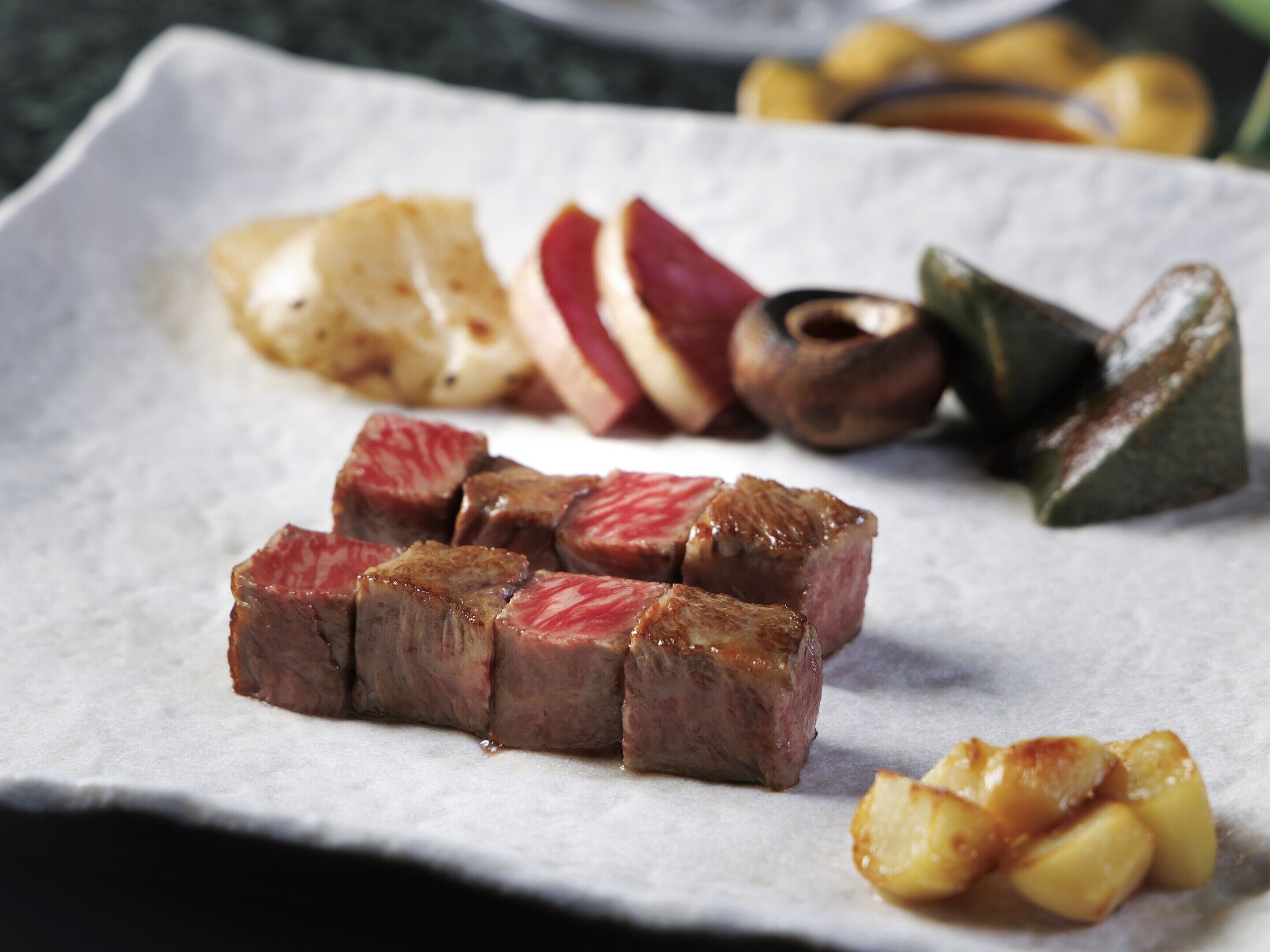A plate with sliced meat, vegetables, and a small bowl of sauce.