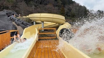A water slide with a wooden deck and a mountainous backdrop.