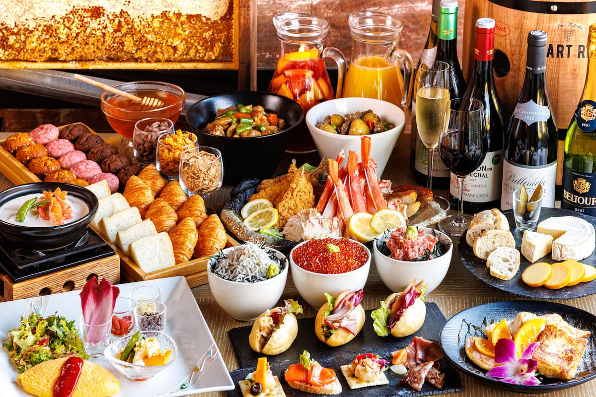 Diverse etenswaren en dranken op een tafel, waaronder gebak, zeevruchten en wijnflessen.