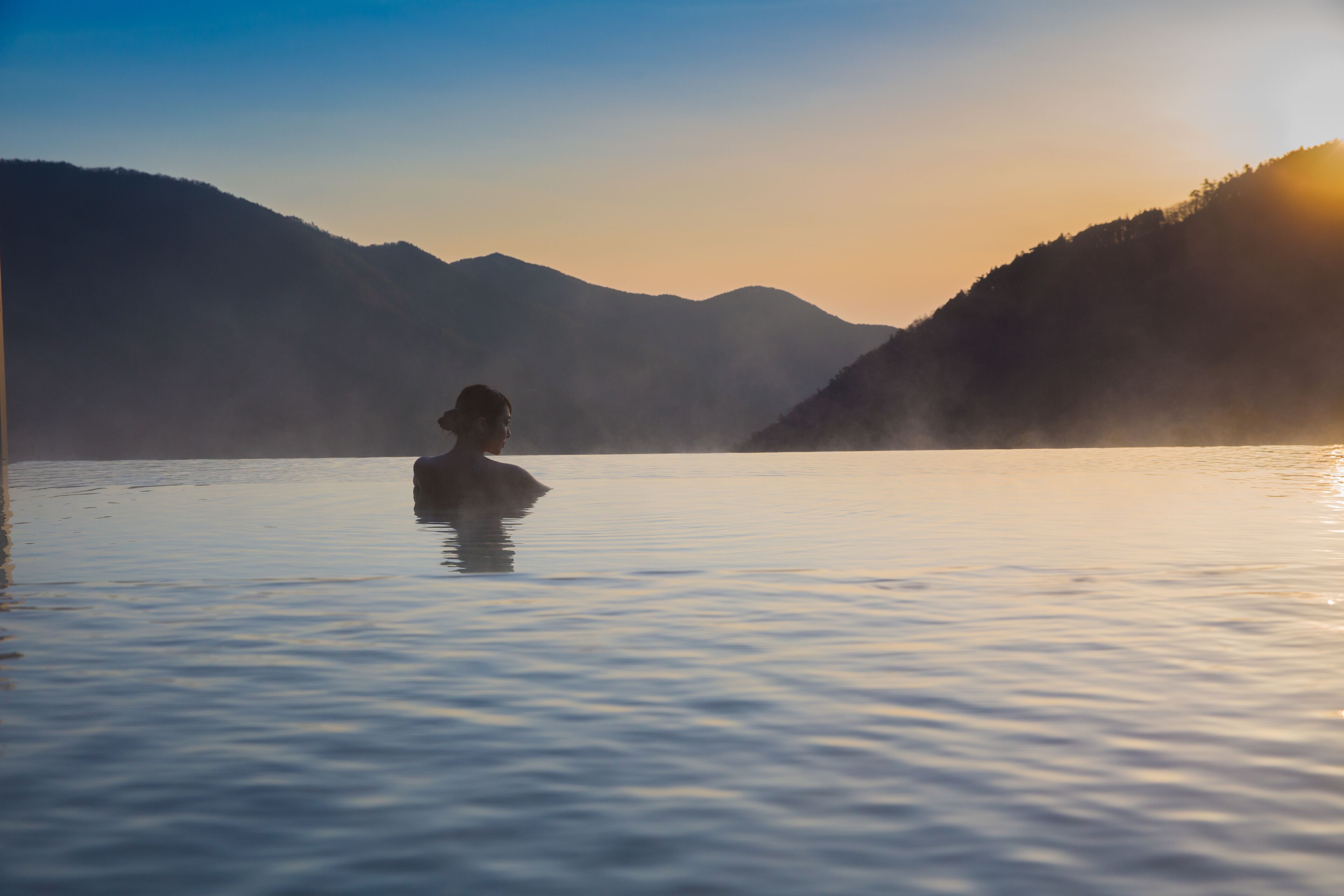 A person in a natural setting with mountains in the background.