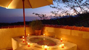Un jacuzzi con velas, una planta en maceta y un paraguas.