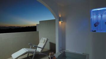 A balcony with a white chair, a bathtub, and a wall-mounted aquarium.