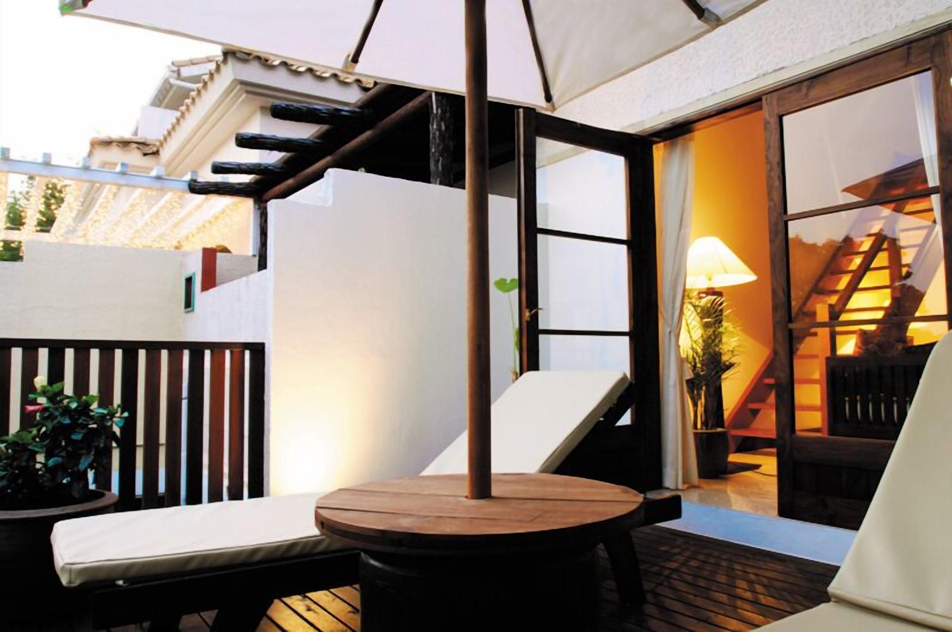 A patio with a round table, a bench, and a lamp.