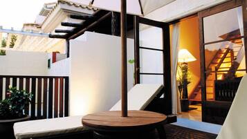 A patio with a round table, a bench, and a lamp.