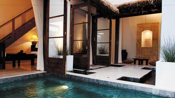 Un área de piscina con terraza de piedra, una escalera y un mostrador de recepción con una lámpara.