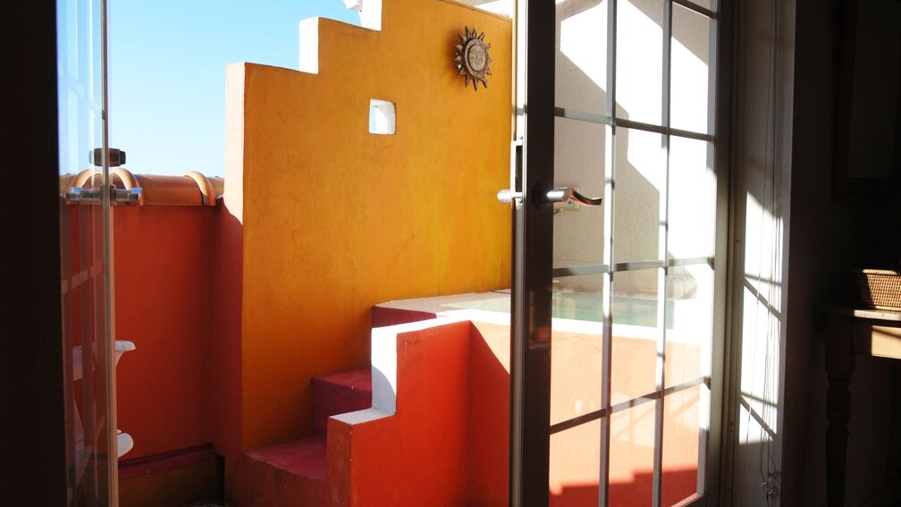 A room with a glass door, a red wall, and a window.