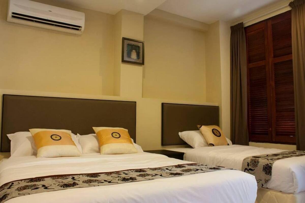 A hotel room with two beds, a large window with curtains, an air conditioning unit, and a framed picture on the wall.